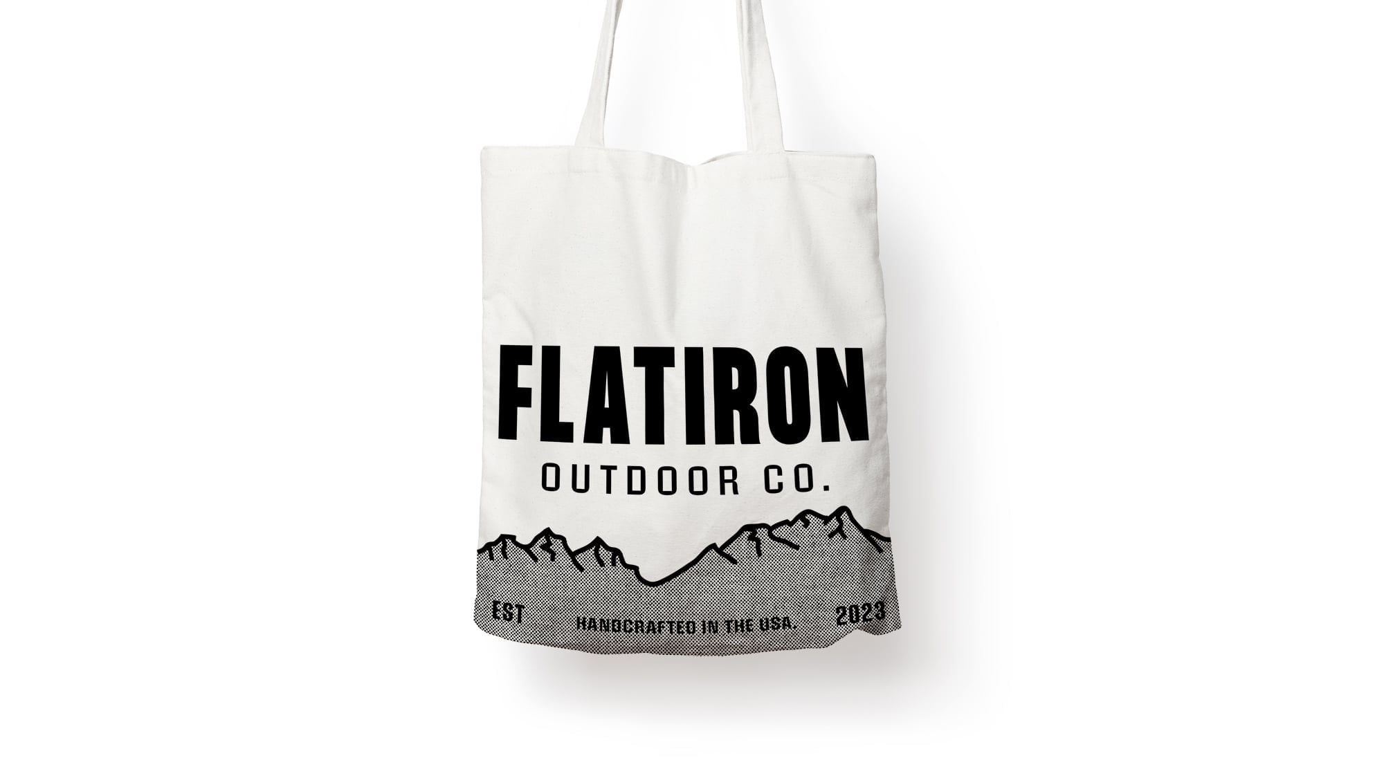 A white heavy-duty canvas tote bag printed with a bold black mountain landscape and Flatiron Outdoor Co. typography.