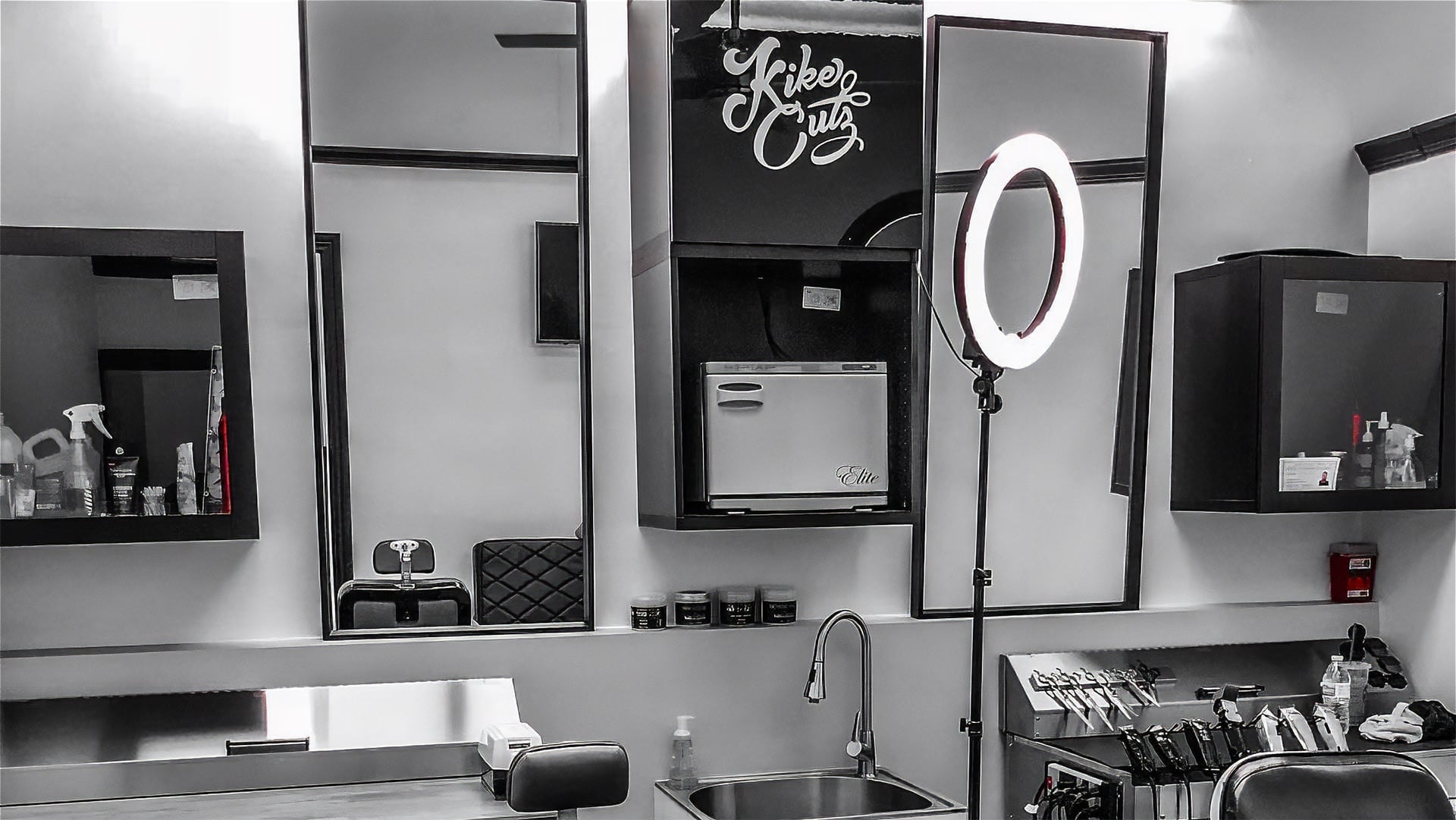 Interior view of the Kike Cutz barbershop, showing modern stations with large mirrors and a professional ring light for detail work.